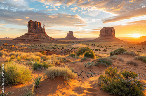 Photo of a Desert landscape with iconic rock formations in the distance in the Arizona desert  with the sun rising behind Monument Valley  Utah