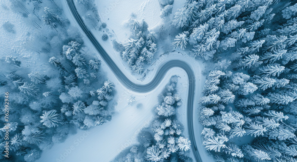 Aerial view of winding road in winter forest, with the shape of snake on snowcovered ground. Aerial drone photo