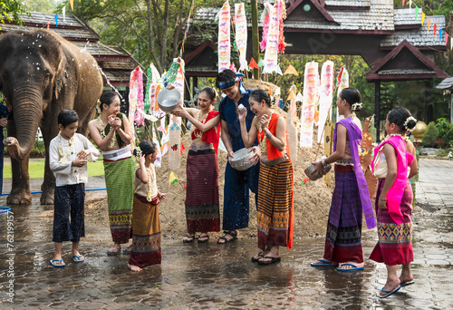 Group of Thai women, man and children in colorful traditional Thai clothing holding silverware bowl splashing water celebrating Songkran festival in Chiangmai thailand