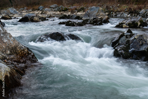 Rapid creek flow around wet rocks, mountain stream during blue hour