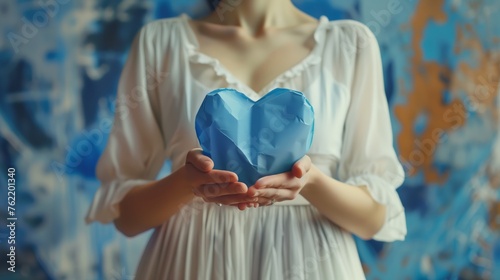 Frau hÃ¤lt ein blaues Papierherz in den HÃ¤nden  photo