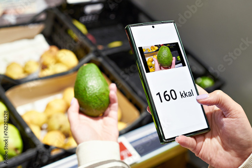 Checking calories on an avocado fruit in store with smartphone