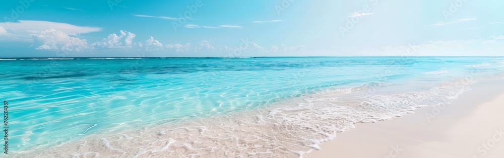A beach featuring clear blue waters and soft white sand, creating a serene and inviting atmosphere. The waves gently wash onto the shore, reflecting the clear sky above.