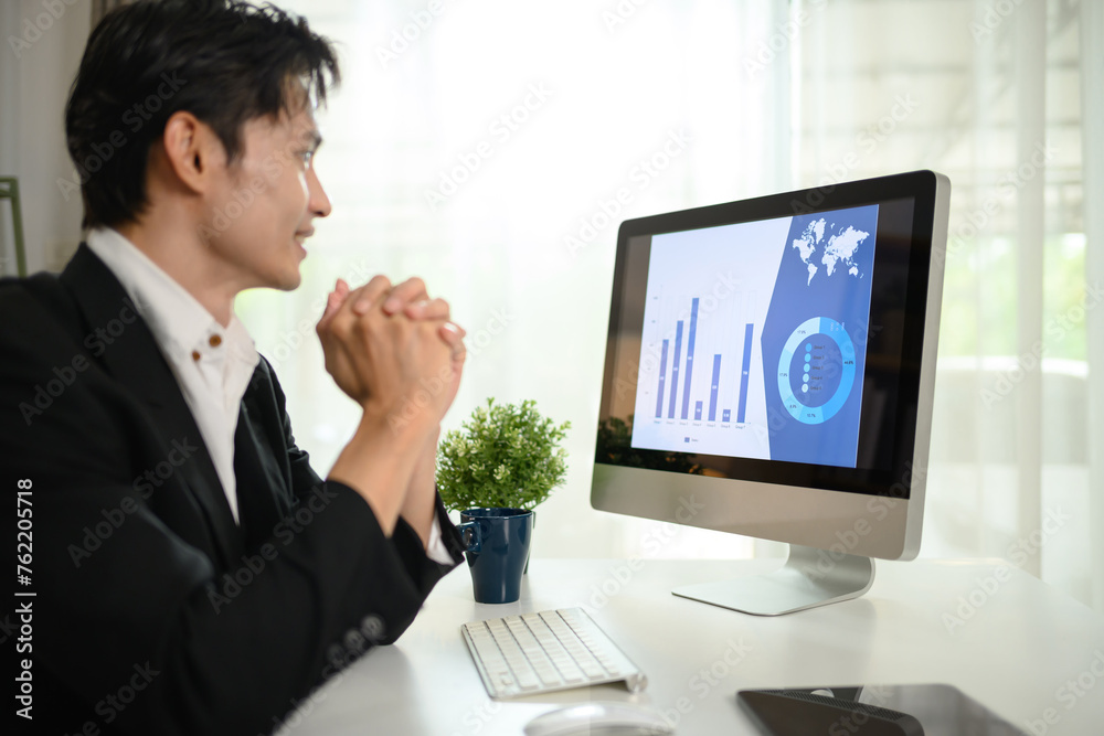 Millennial male investor checking trade market data on computer monitor Millennial male investor checking trade market data on computer monitor