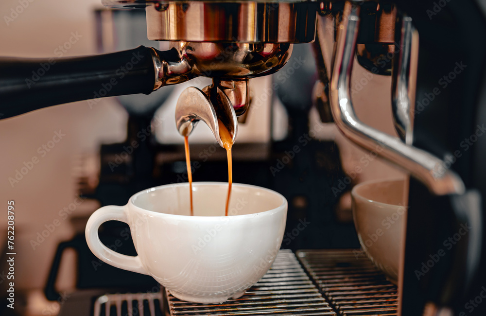 Coffee extraction from the coffee machine with a portafilter pouring coffee into a cup,Espresso poruing from coffee machine at coffee shop