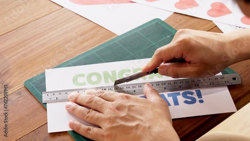 Close-up of hands cutting paper using utility knife cutter with ruler on cutting mat. photo