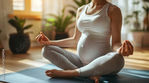 Pregnancy relaxation exercises meditation  background - Close up of pretty young pregnant woman with pregnancy belly, practicing yoga exercises, sits cross-legged on teh floor in living room at home