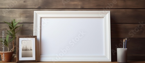 A brown rectangle picture frame sits on a wooden table next to a plant and a candle, creating a cozy fixture in the interior design of the room