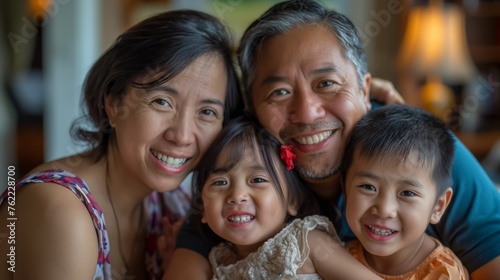 A joyful Asian family with two children sharing a warm embrace, radiating happiness and togetherness in an indoor setting.