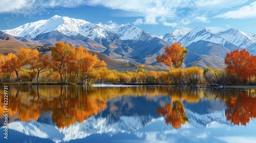 A tranquil lake reflecting the surrounding snow-capped mountains, with a few colorful autumn trees lining the shore.