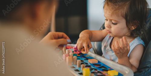 Portrait happy little girl playing activity skill brain training play with toy build wooden blocks board education game. Correct puzzle piece in seguin board photo