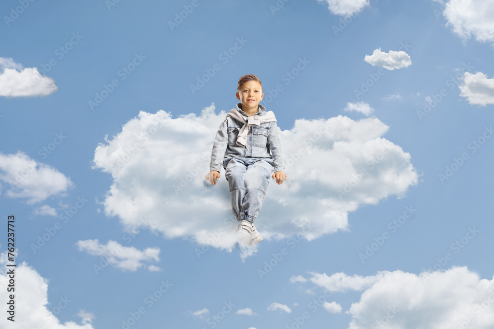 Little boy in jeans floating on a cloud