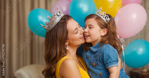 Joyful mother and daughter posing playfully, with colorful accessories and crown, capturing the spirit of mother's day humor and happiness.
