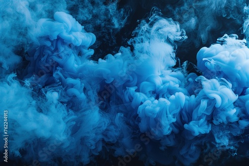 A thick cloud of blue smoke drifting across a black back photo