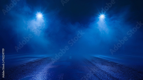 A dark empty street, blue background, dark scene, neon light, spotlights. The asphalt floor and studio room