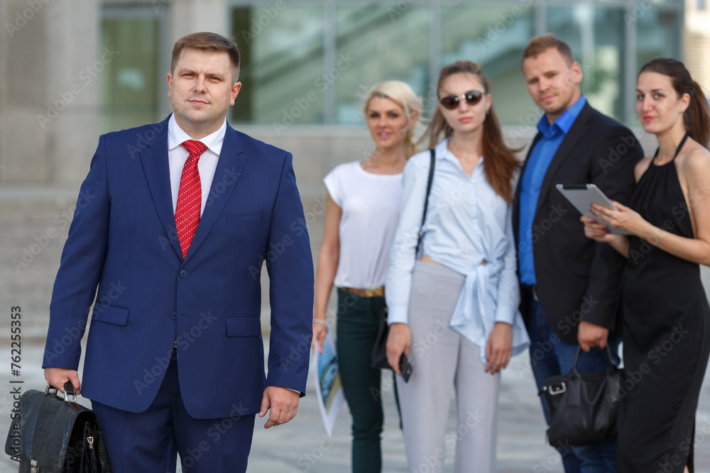 well dressed business team leader and four co-workers in background