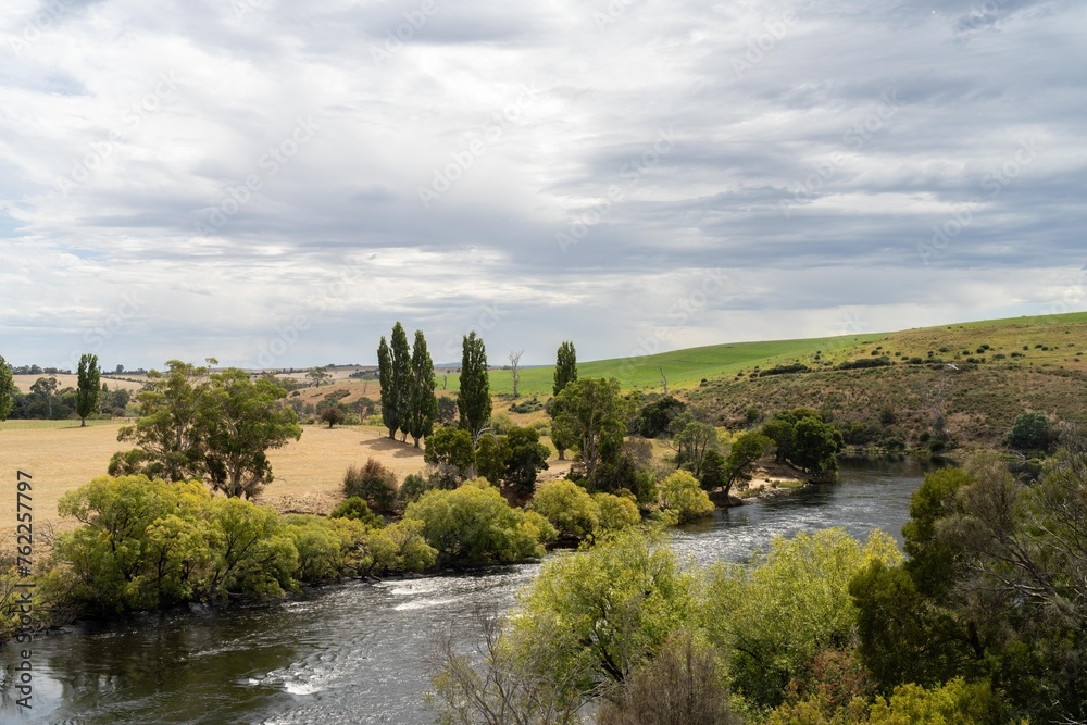 flowing river past farmland in summer, in the Tasmania wilderness. Lake with a Sandy beach and trees in Australia
