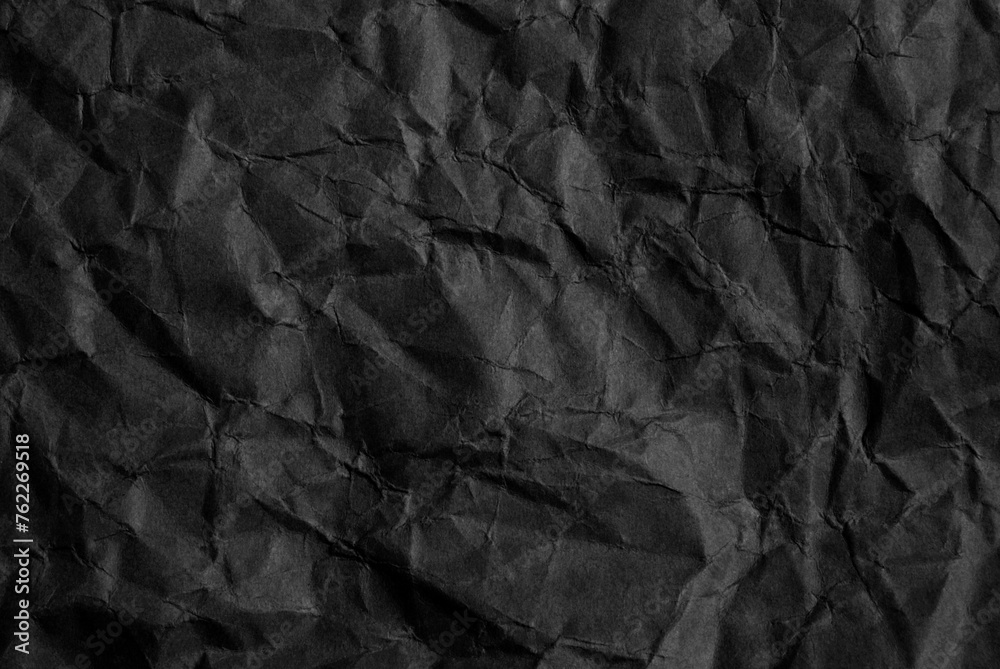 A sheet of wrinkled black color paper texture as background A sheet of wrinkled black color paper texture as background
