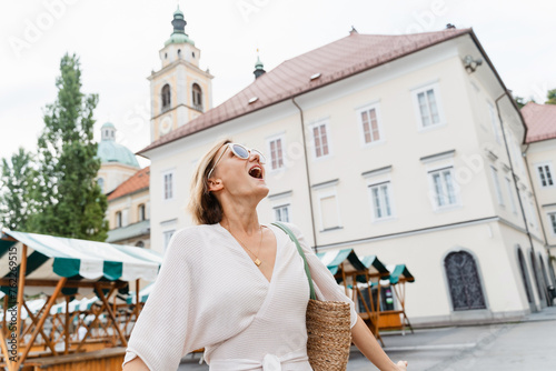 Smiling woman wearing stylish outfit walking on street of Ljubljana old town, Slovenia.Travel Europe photo