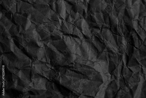 A sheet of wrinkled black color paper texture as background