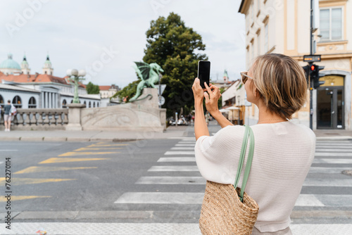 Woman taking photo on smartphone of Dragon bridge (Zmajski most), symbol of Ljubljana, Slovenia photo