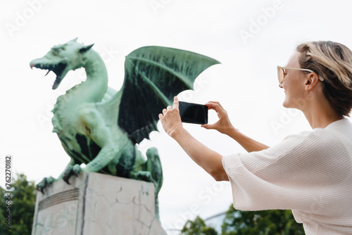 Woman taking photo on smartphone of Dragon bridge (Zmajski most), symbol of Ljubljana, Slovenia photo