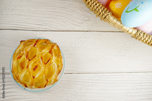 Easter Eggs in the basket with bakery cake fresh baked on white wooden table background