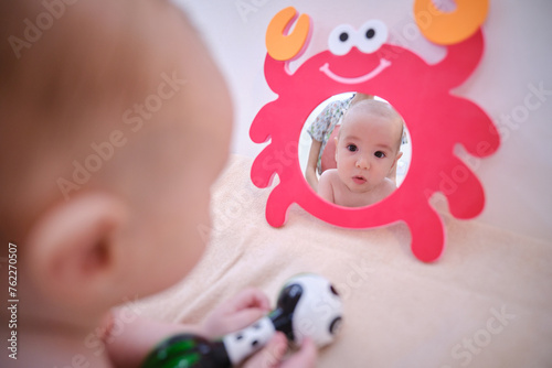 A baby is looking at a mirror with a crab on it