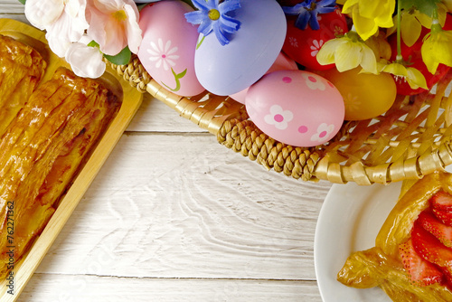 Easter Eggs in the basket with bakery cake fresh baked on white wooden table background