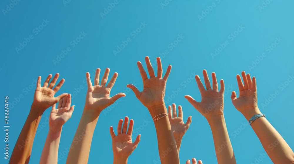 Energetic hands reaching up against a clear blue sky, reflecting hope and collective effort. Group of young people's hands raised, outdoors