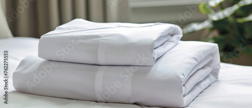 Neatly folded white cotton bed sheets in a stack of three, ready to be used. © Szalai