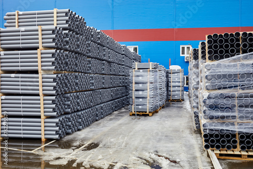 Plenty of grey plastic water pipes at outdoor storage.