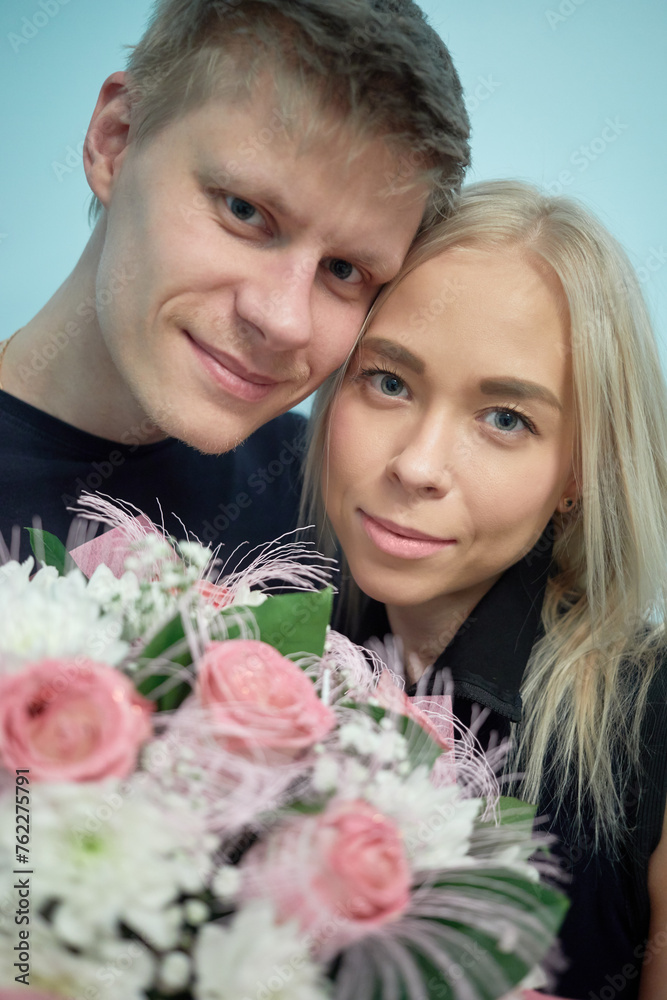 Portrait of happy young couple with bunch of flowers.