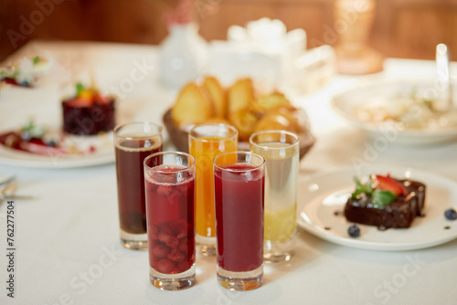 Several kinds of fruit beverages in glasses and cakes on table  shallow dof.