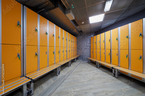 Room with rows of orange lockers at fitness center. photo