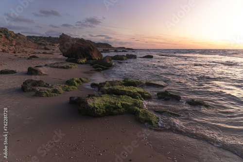  landscape of mossy rocks on seashore on a windy evening golden hour