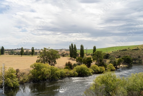 flowing river past farmland in summer  in the Tasmania wilderness. Lake with a Sandy beach and trees in Australia