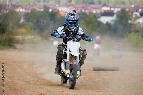 Foto Several boys ride motorbikes on dusty track road.