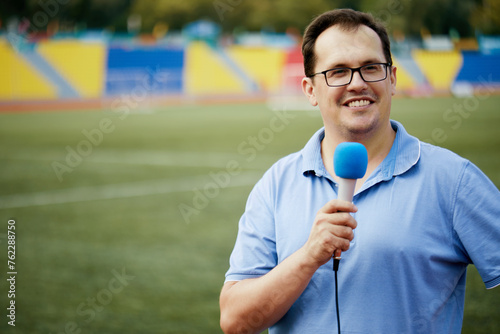 Smiling sportscaster with microphone is reporting from stadium. photo