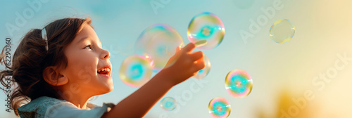 joyful girl catches soap bubbles with her hands, space for text, background for banner