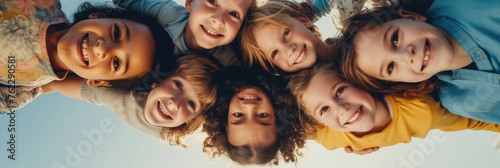 a children's group of friends are standing in a group, smiling, filmed from below © yanapopovaiv