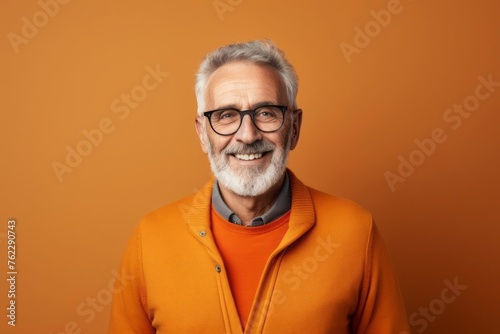 Happy smiling elderly man with short beard and glasses standing in the living room