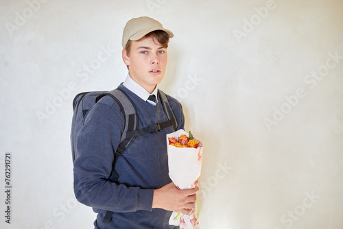 Tableau sur toile Portrait of schoolboy in cap with rucksack and bunch of flowers.