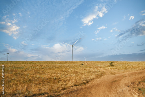 Wind turbines in the field against a blue sky in summer.