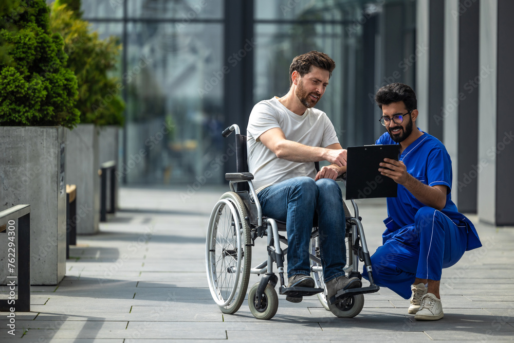 Man sitting in a wheelchair and discussing something with male nurse Man sitting in a wheelchair and discussing something with male nurse