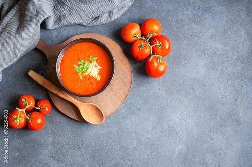 Tomato soup in bowl with fresh organic tomatoes on table, healthy homemade traditional soup	