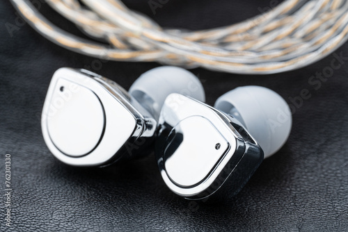 In ear monitor on a tablature background. Custom in-ear monitors with black plates. Custom in ear monitors or IEMs ready for a musician to wear on stage at a concert.	
 photo