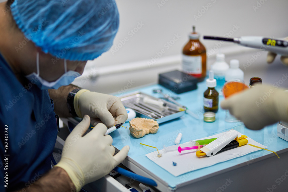 Dentist and assistant prepare dental implant on medical table. Dentist and assistant prepare dental implant on medical table.
