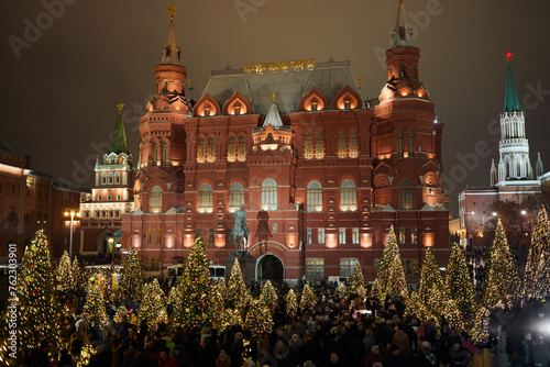 People walk in evening on Manezhnaya square near Historical museum during Christmas and New Year holidays.