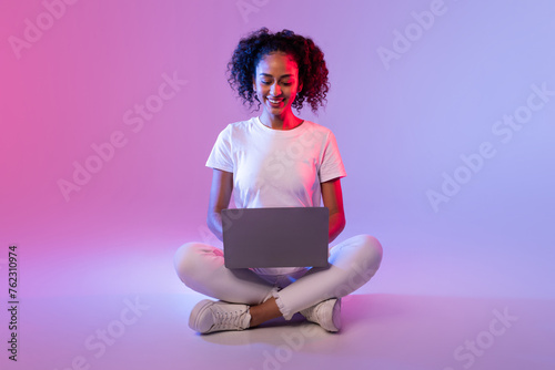 Smiling woman sitting with laptop on floor